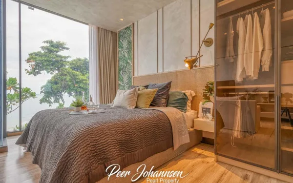 Arom Wongamat: Bedroom with a bed, open wardrobe, and floor-to-ceiling windows offering an ocean view.