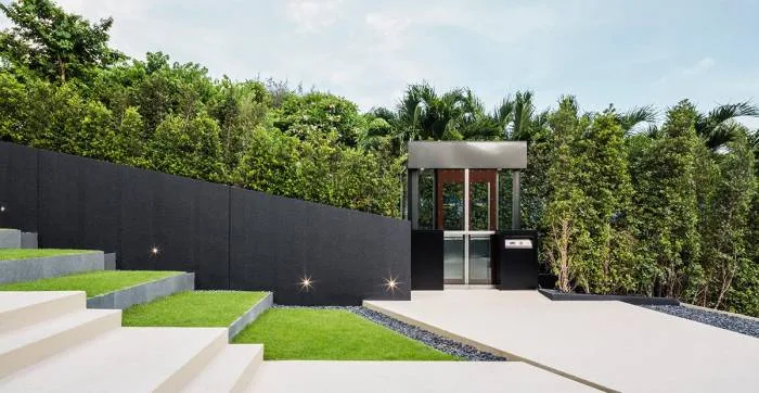 Baan Plai Haad large outdoor swimming pool with trees, modern building entrance, and city skyline.