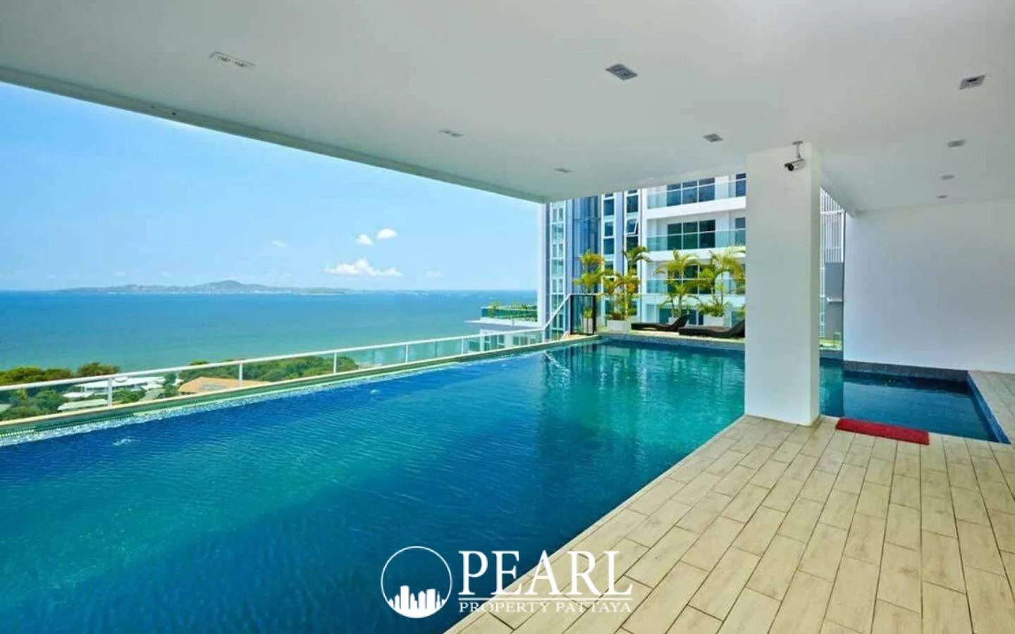 Cosy Beach View indoor-outdoor swimming pool overlooking the ocean, with a smaller pool and modern building architecture